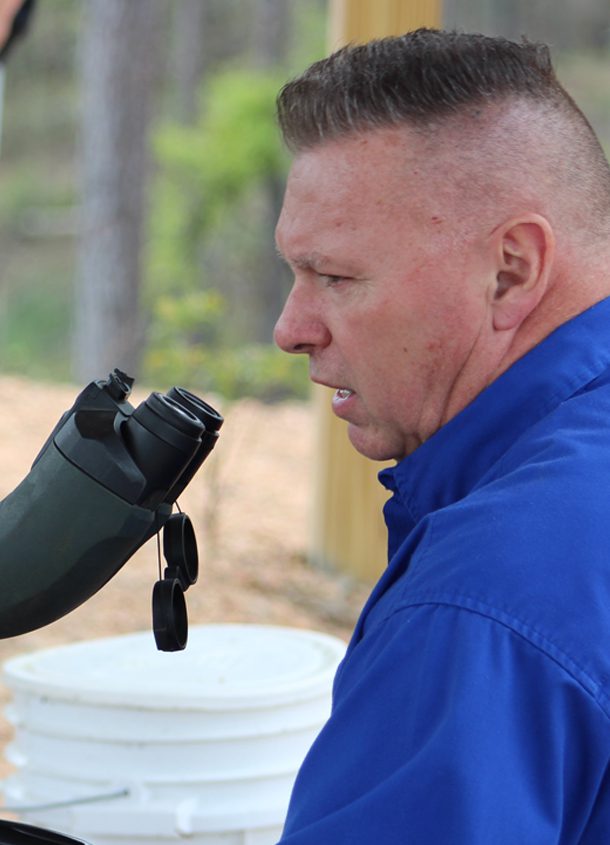 A man drinking water from a cup while standing outside.