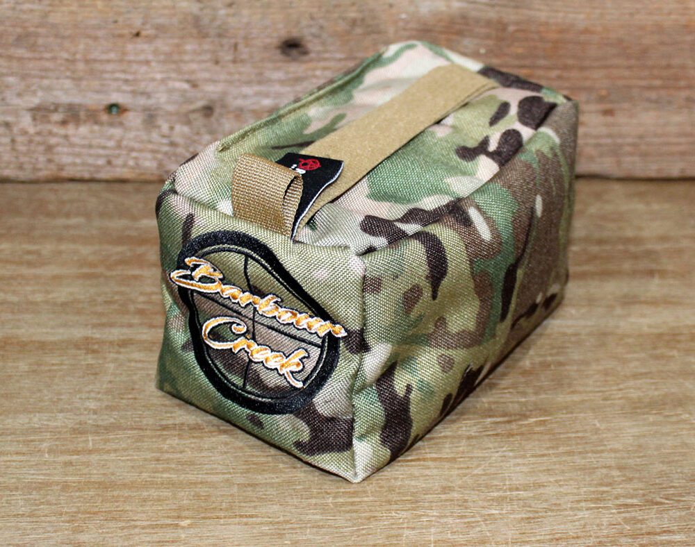 A small camouflage bag sitting on top of a wooden table.