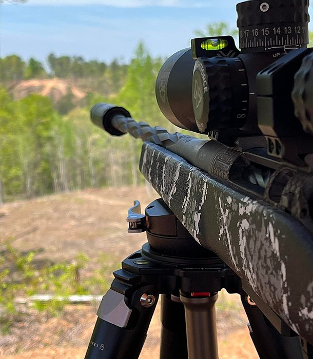 A rifle with a scope on it's tripod.